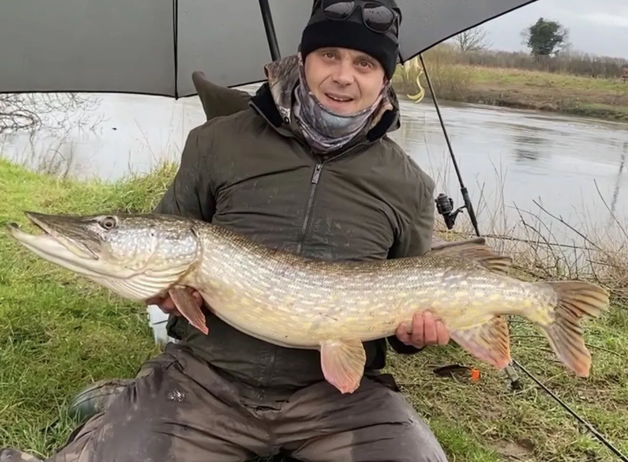 Dean Lutwyche holding his 23lb 8oz club record pike on the riverbank